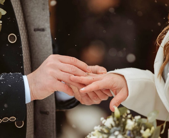 Bräutigam zieht den Hochzeitsring über den Finger der Braut